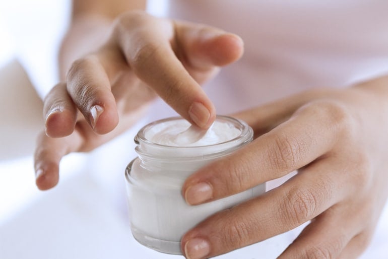 Woman reaching into a jar of SPF moisturizer