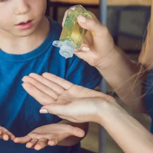 Mother using homemade hand sanitizer with son