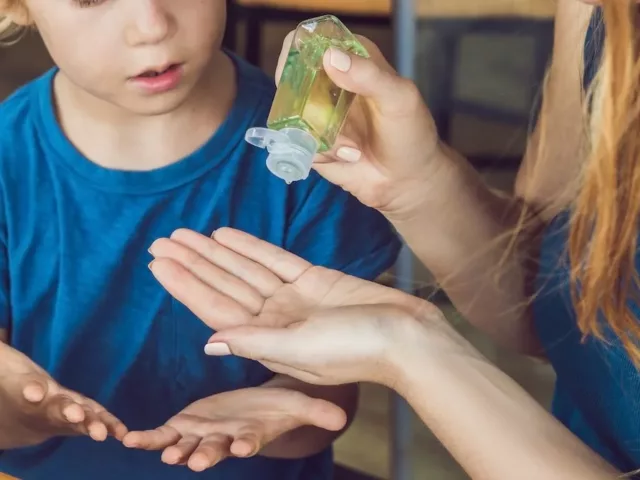 Mother using homemade hand sanitizer with son