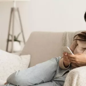 Woman listening to podcasts on her couch