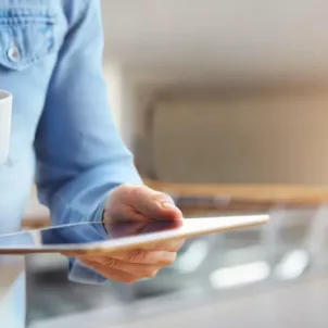 Man reading the news on tablet while drinking coffee