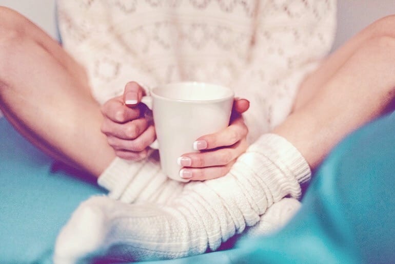 Girl in bed drinking tea and supplementing with valerian root for sleep