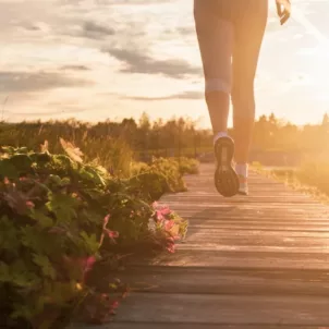 Woman walking on a wooden path in nature before dusk to reap the surprising benefits of walking daily