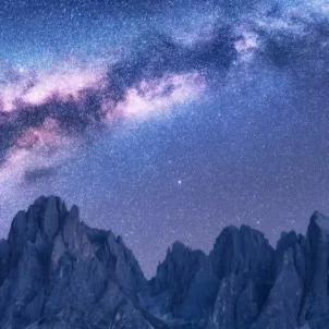 Purple and blue starry night sky above mountains