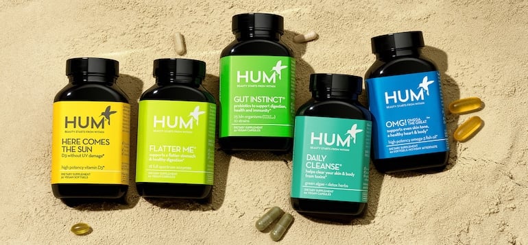 HUM Nutrition supplement bottles on the sand to illustrate our transition to 100% ocean-bound plastics