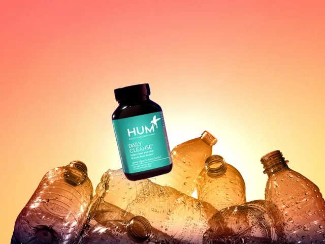 HUM Daily Cleanse supplement on top of empty plastic bottles to demonstrate HUM's transition to 100% ocean-bound plastic