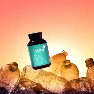 HUM Daily Cleanse supplement on top of empty plastic bottles to demonstrate HUM's transition to 100% ocean-bound plastic