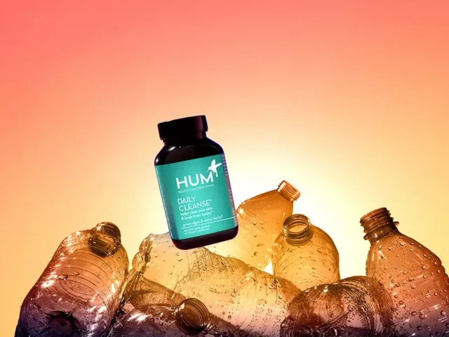 HUM Daily Cleanse supplement on top of empty plastic bottles to demonstrate HUM's transition to 100% ocean-bound plastic