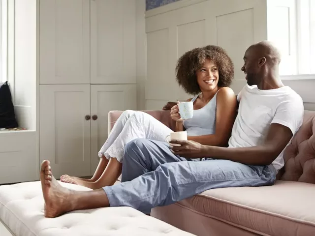 Young couple smiling at home with coffee, benefiting from human connection