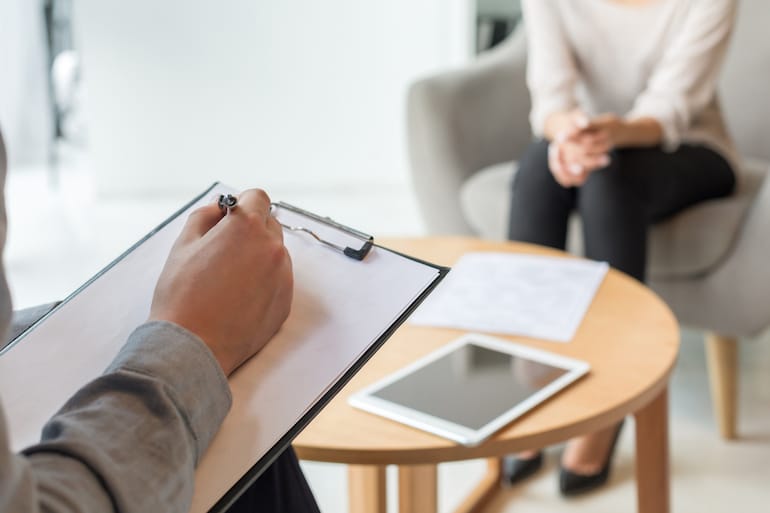 Woman in a mental health therapist session while therapist takes notes