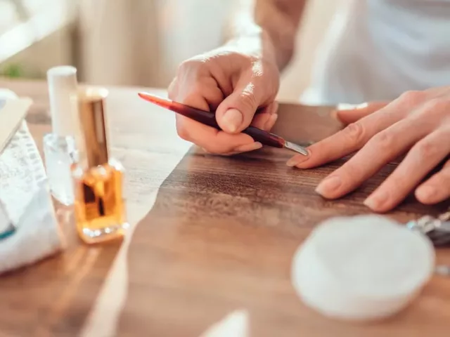 Woman removing her gel manicure at home and pushing her cuticles