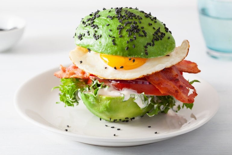 Keto diet meal with avocado, egg, bacon, and black sesame seeds