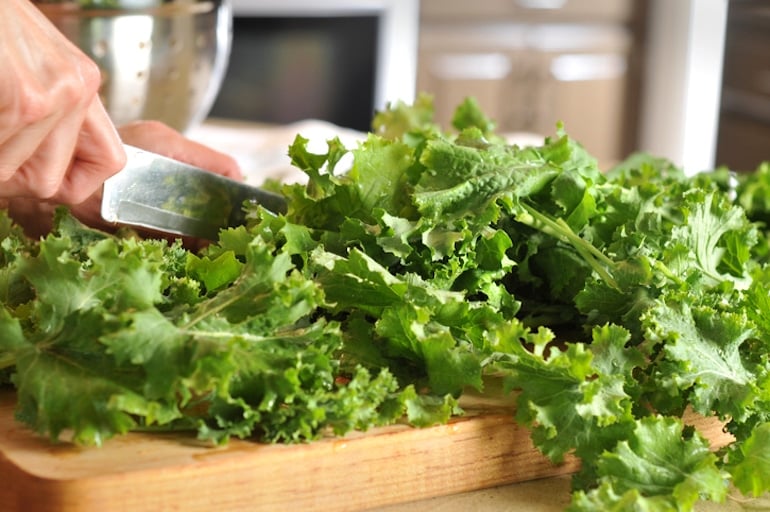 Woman chopping kale to put into a vitamin C smoothie for an immune booster