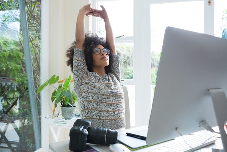 Woman doing overhead stretches at her desk