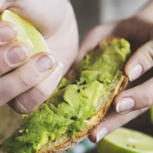 Woman squeezing a lemon onto avocado toast