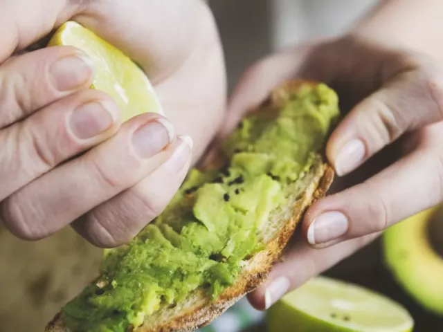 Woman squeezing a lemon onto avocado toast