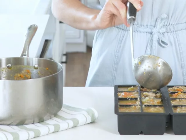 Miriam Jacobson, MS, RD, CNS, ladling chicken vegetable soup into silicone trays for the best way to freeze soup
