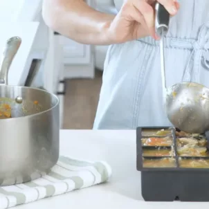 Miriam Jacobson, MS, RD, CNS, ladling chicken vegetable soup into silicone trays for the best way to freeze soup