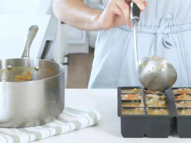 Miriam Jacobson, MS, RD, CNS, ladling chicken vegetable soup into silicone trays for the best way to freeze soup