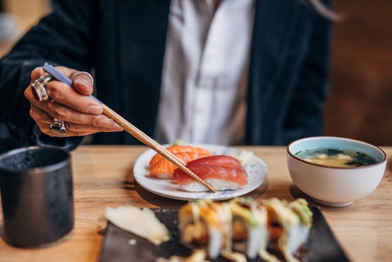 Man eating sushi with fatty fish in restaurant