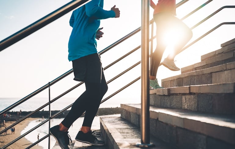 Man and woman running up the steps, a natural way to relieve constipation is through movement