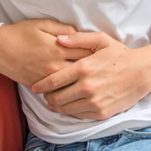 Man feeling unwell on couch touching his stomach to emphasize connection between gut health and immune system