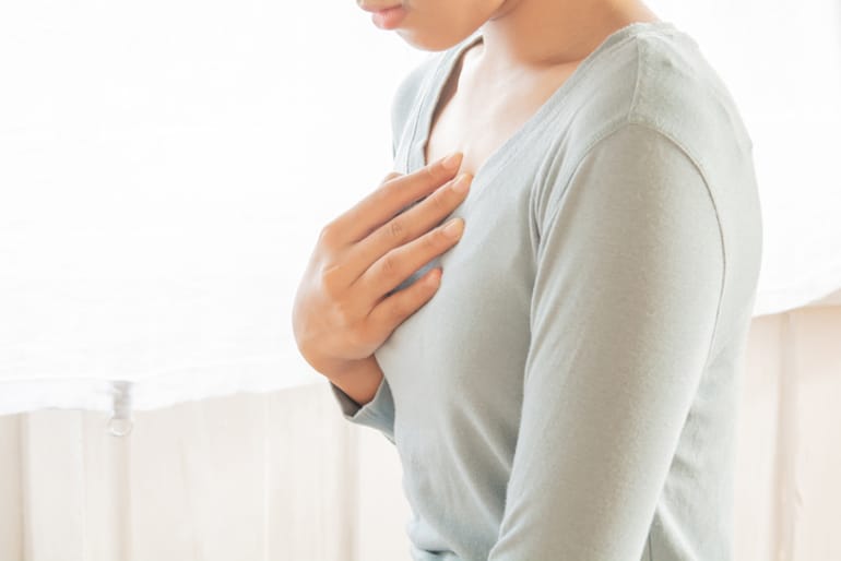 Woman clutching her chest in pain from heartburn