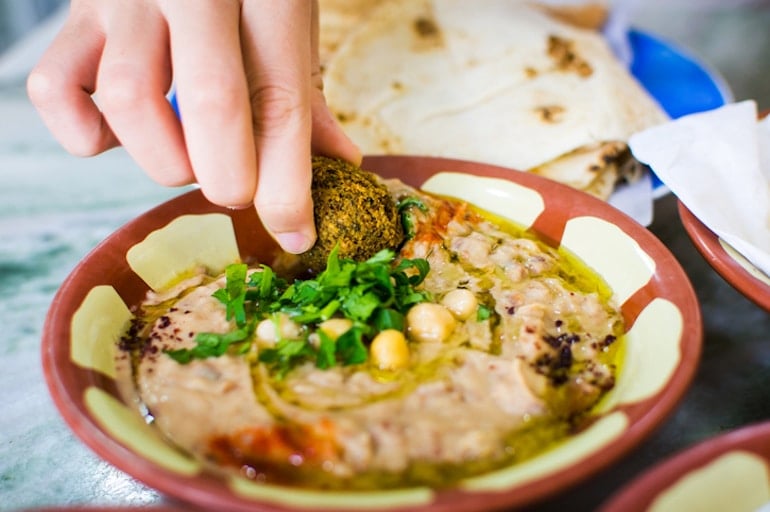 Woman eating falafel and hummus with olive oil, rich with healthy fats and fiber for optimal gut health