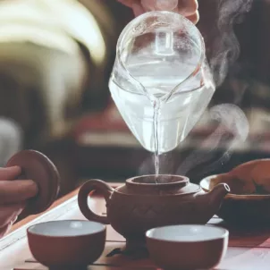 Woman pouring hot water to brew tea, one of the approved drinks on a bland diet to help prevent heartburn