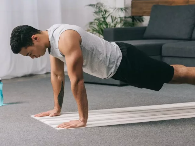 Man in plank pose on a yoga mat at home