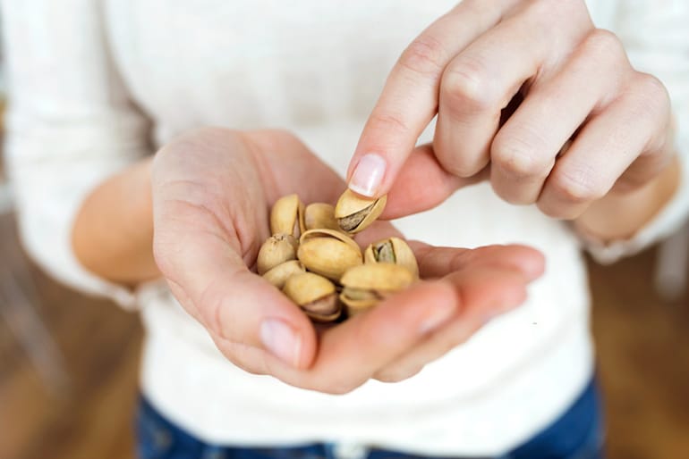 Woman with pistachios in hand, among the best foods to reduce stress