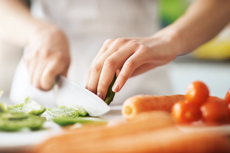 Woman chopping vegetables with knife at an angle