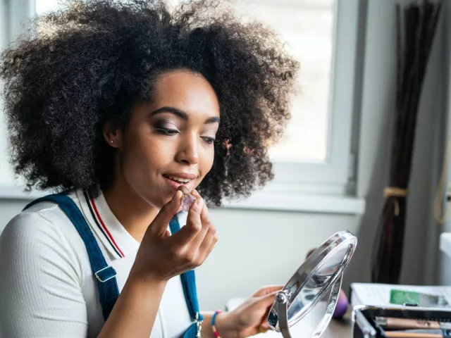 Woman applying makeup at home