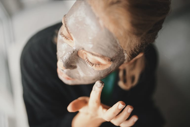 Woman applying a clay mask, one of the best tips for clear skin and treating blackheads