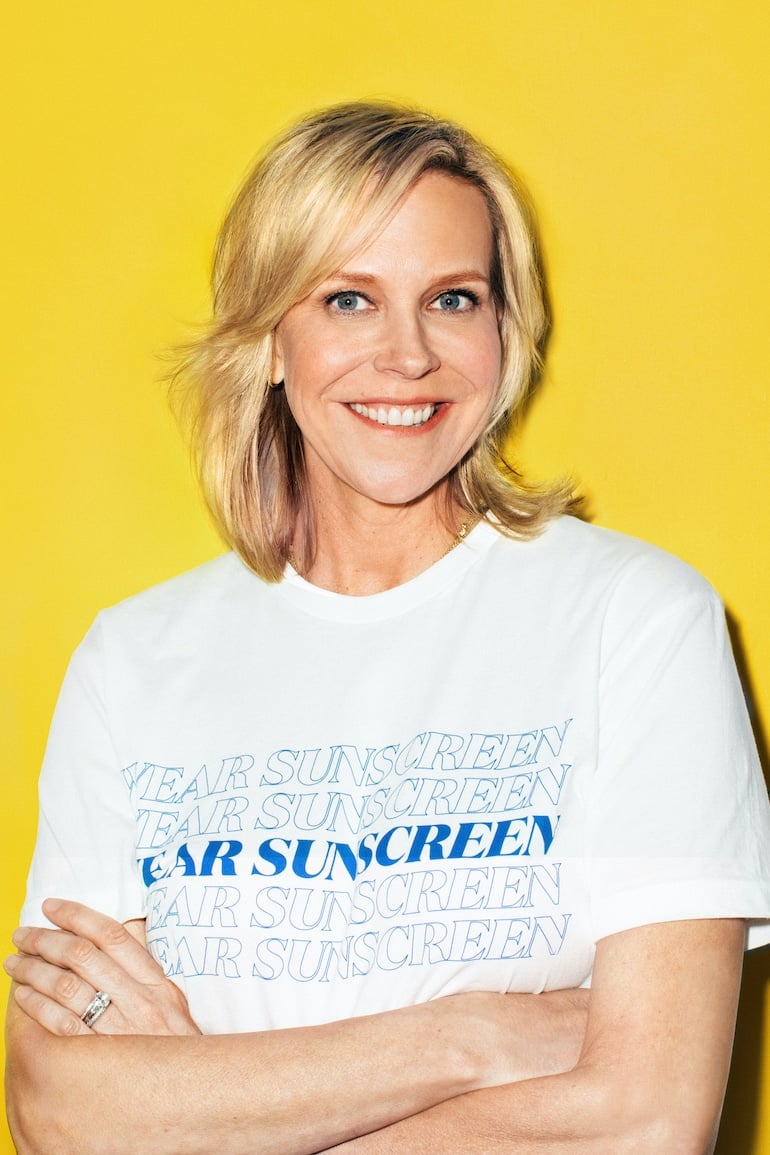 Supergoop! Founder Holly Thaggard in front of yellow background wearing shirt that says "wear sunscreen"