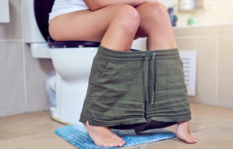 Woman on toilet with the concept of the final intestinal phase of digestion