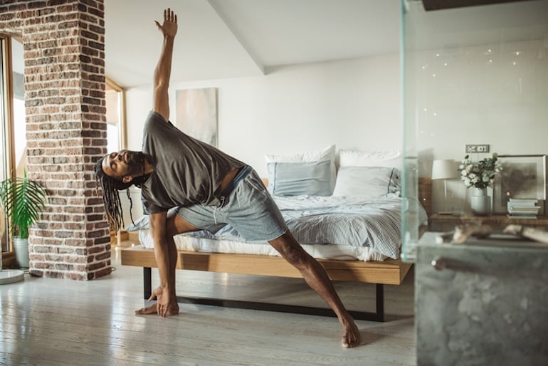 Man in yoga triangle pose for positive time alone to help balance work and life