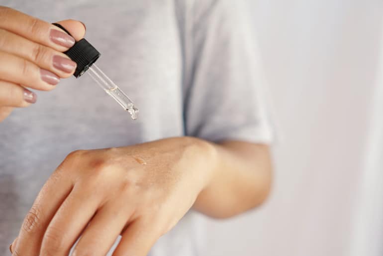 Woman applying serum to back of her hand after taking it out of her mini skincare fridge