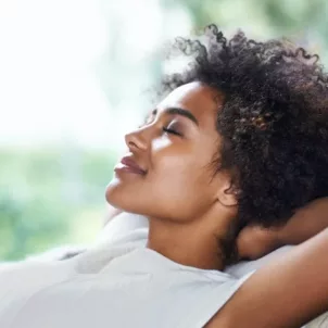 Woman with eyes closed relaxing on couch and practicing self-love