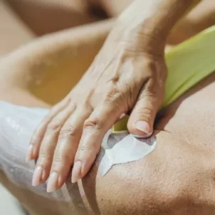 Woman in bikini on chair applying Supergoop! SPF