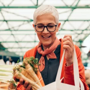 Older woman shopping for produce at the farmers market, looking for approved foods to eat on the Galveston Diet for weight loss and menopause