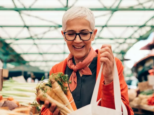 Older woman shopping for produce at the farmers market, looking for approved foods to eat on the Galveston Diet for weight loss and menopause