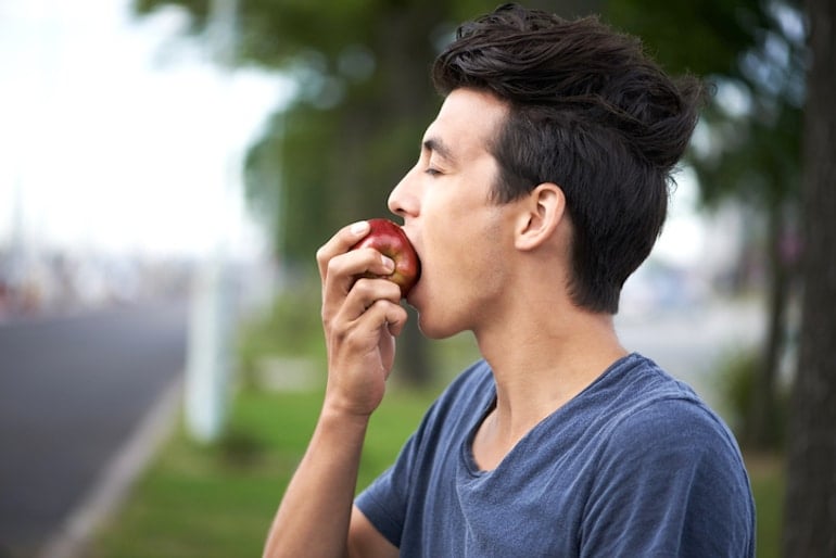 Man taking a bite of an apple to illustrate how digestion works and the importance of chewing for digestive health