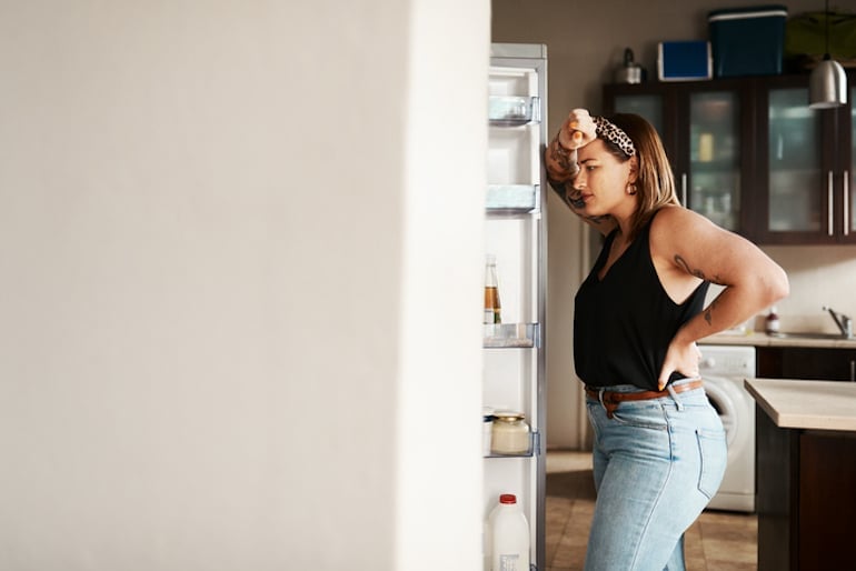 Woman looking into fridge hoping to indulge her carb and sugar cravings due to blood sugar imbalance