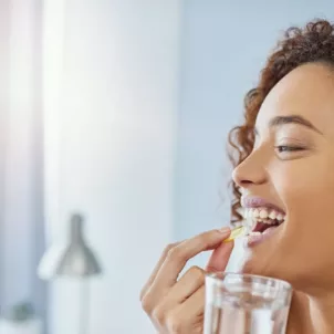 Woman taking a supplement with water to ensure she meets her nutritional needs