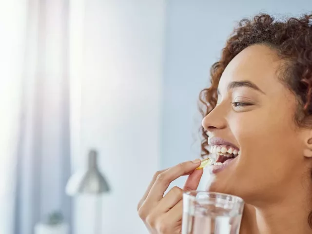 Woman taking a supplement with water to ensure she meets her nutritional needs