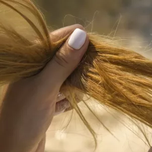 Red-headed woman looking at her hair and wondering how to make your hair less greasy