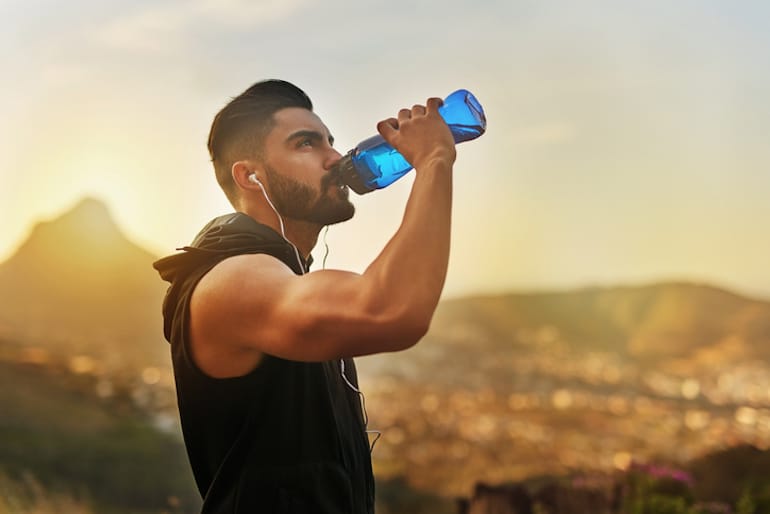 Man drinking water on a hike even though he is intermittent fasting