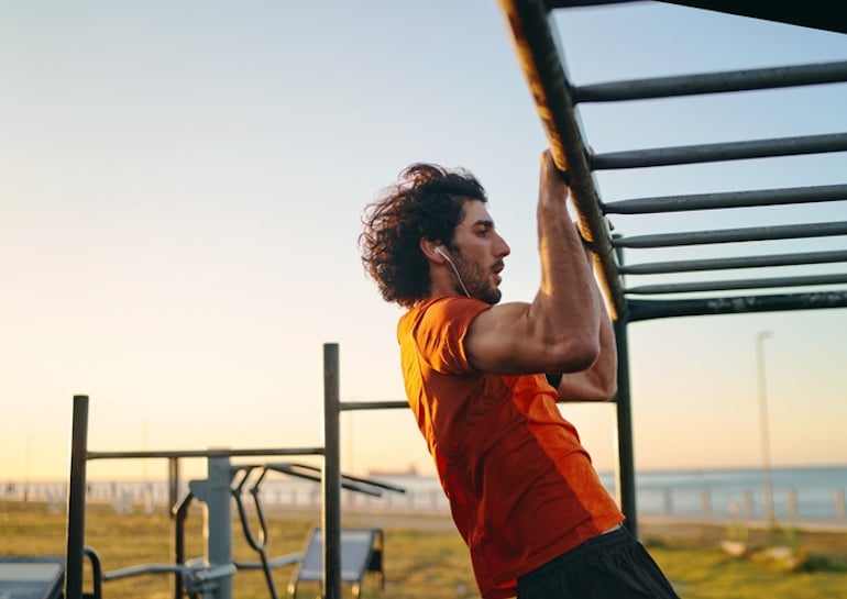 Man doing functional training pull ups at an outdoor gym