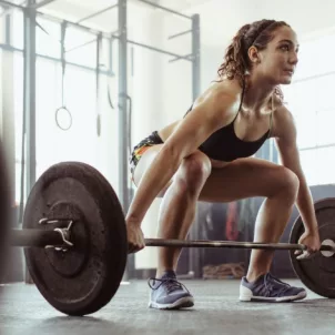 Woman doing deadlifts at the gym to complete her functional fitness routine